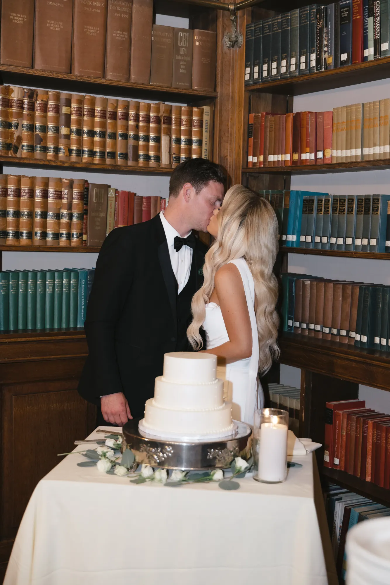 A kiss at the cake table among the books