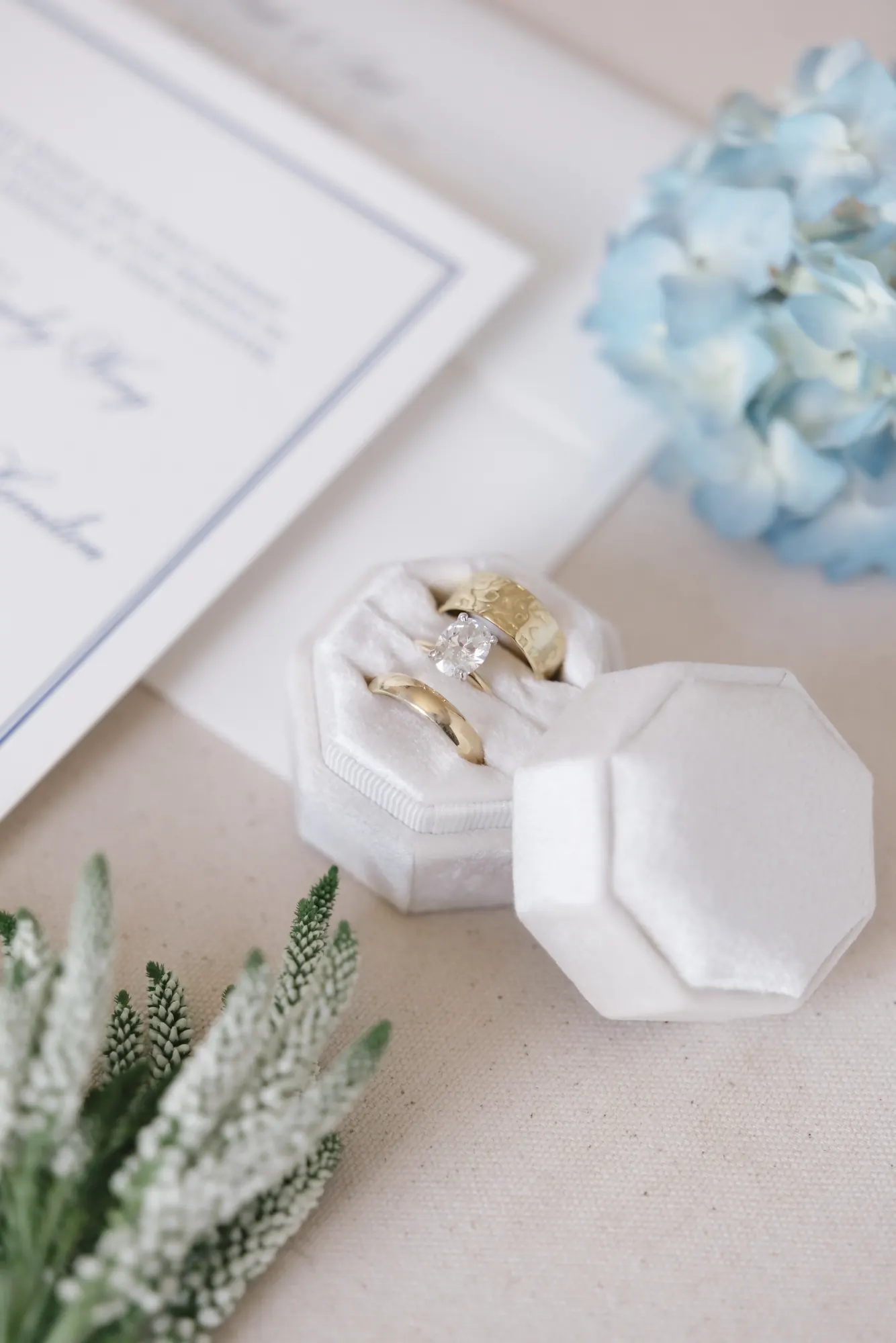 Detail of the wedding bands in an octagonal ring box beside the invitations