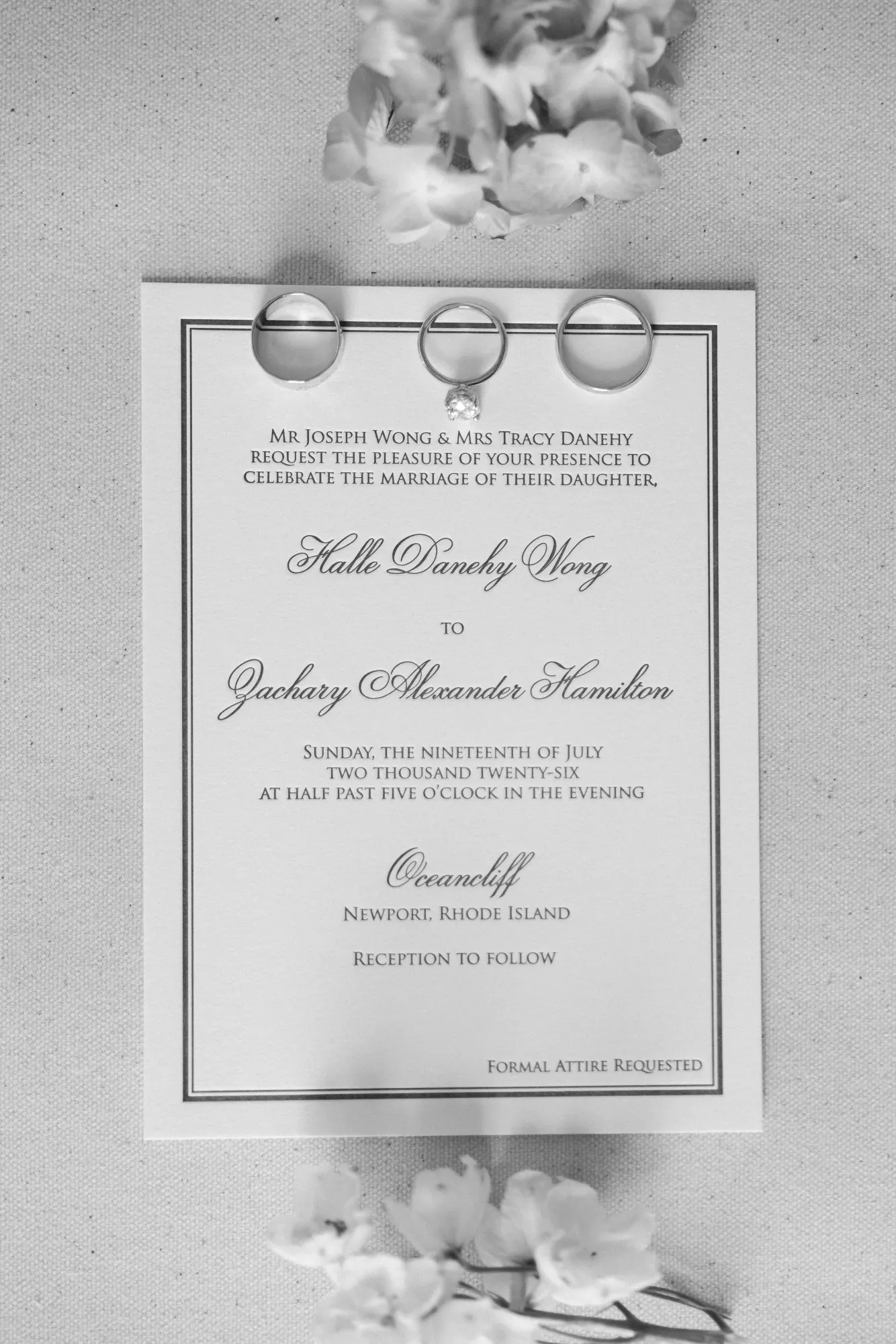 Black and white invitation flat lay with rings and florals