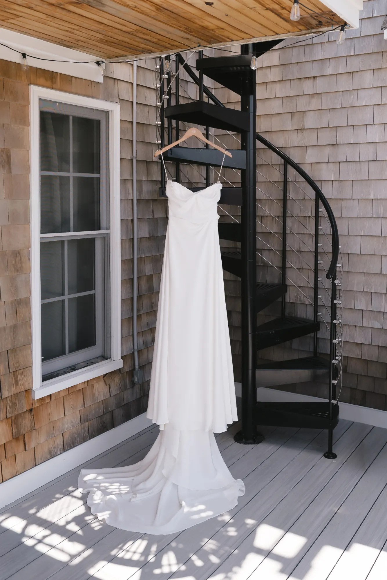 The bride's gown hangs from a spiral staircase at the shingled Newport cottage