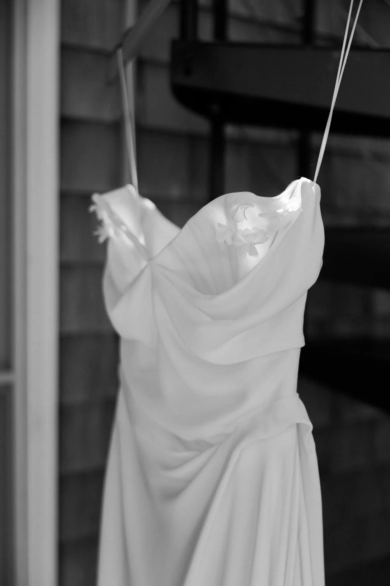 Black and white detail of the wedding gown hanging outdoors