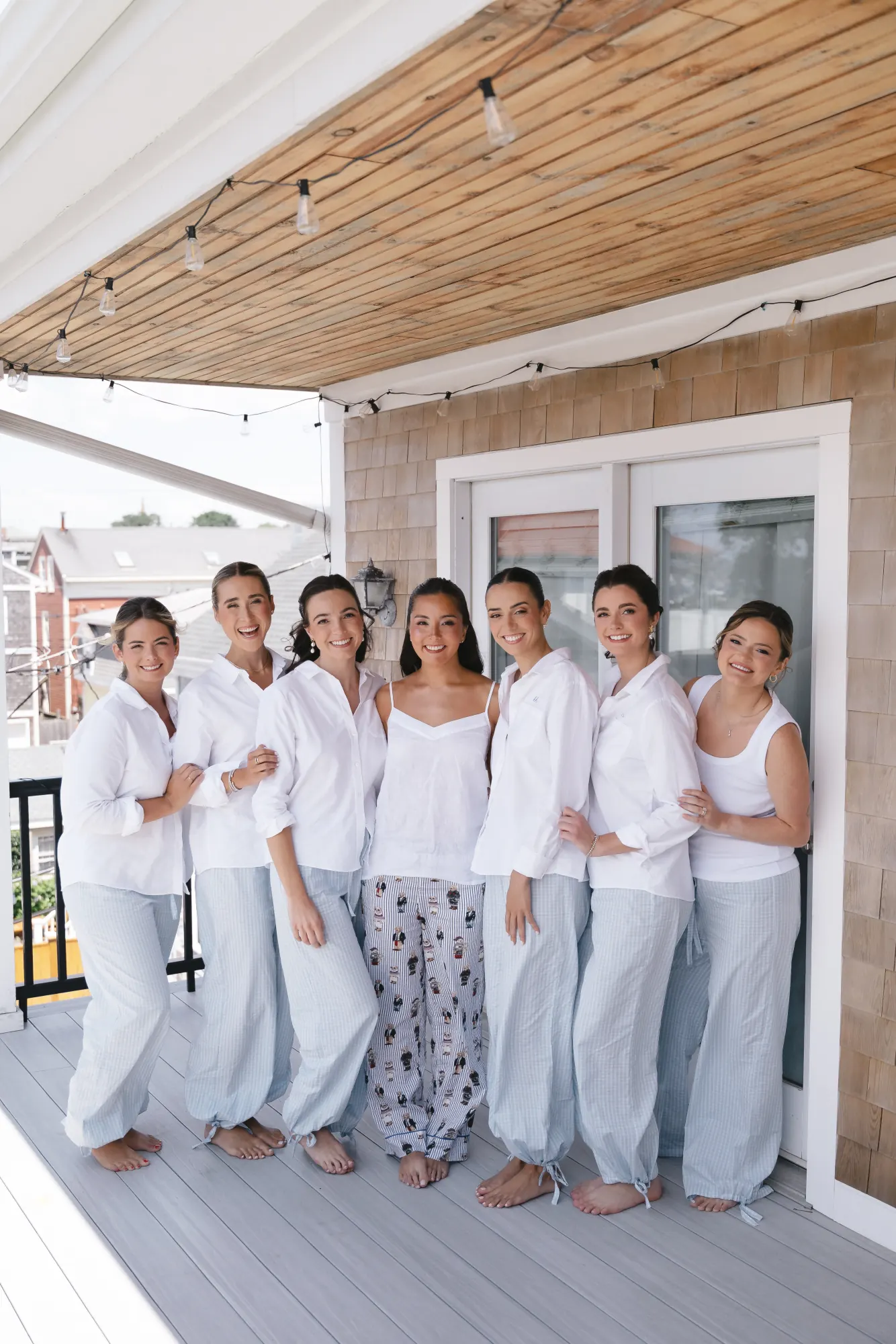 Bride and bridesmaids in white on the porch of the Newport getting-ready cottage