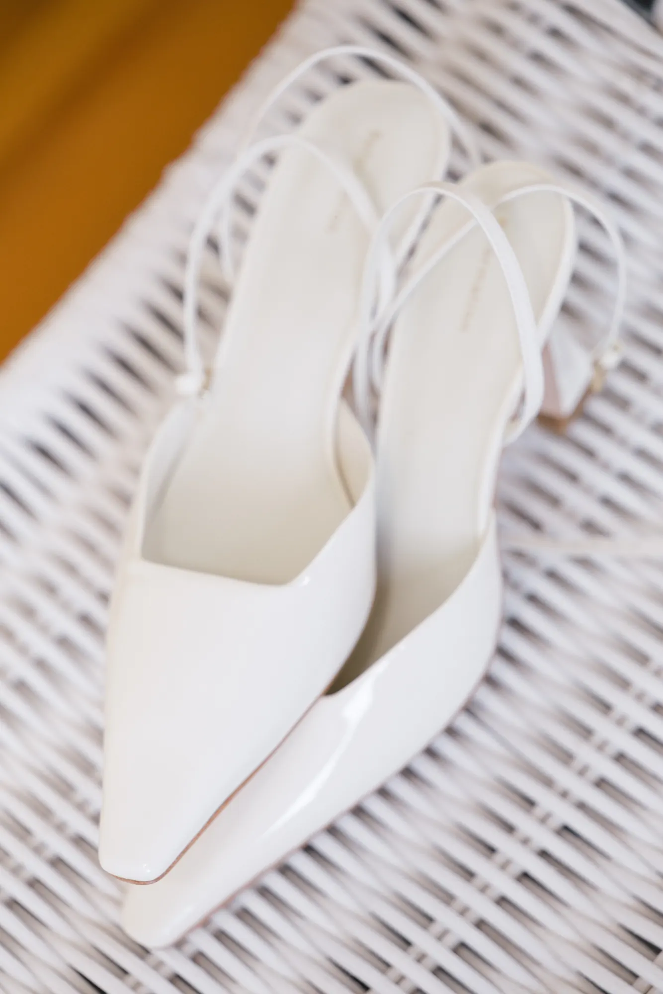 The bride's white heels styled on a wicker chair