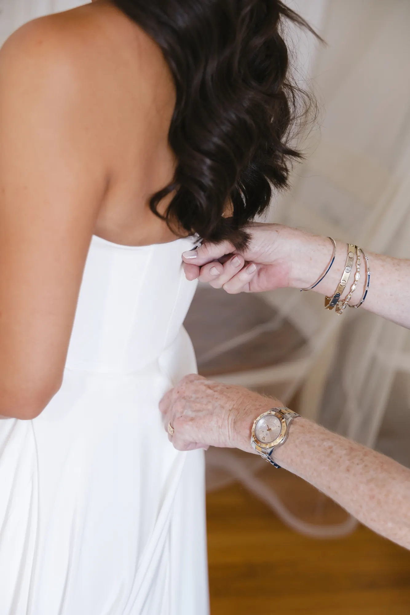 Close detail of hands fastening the back of the bride's gown