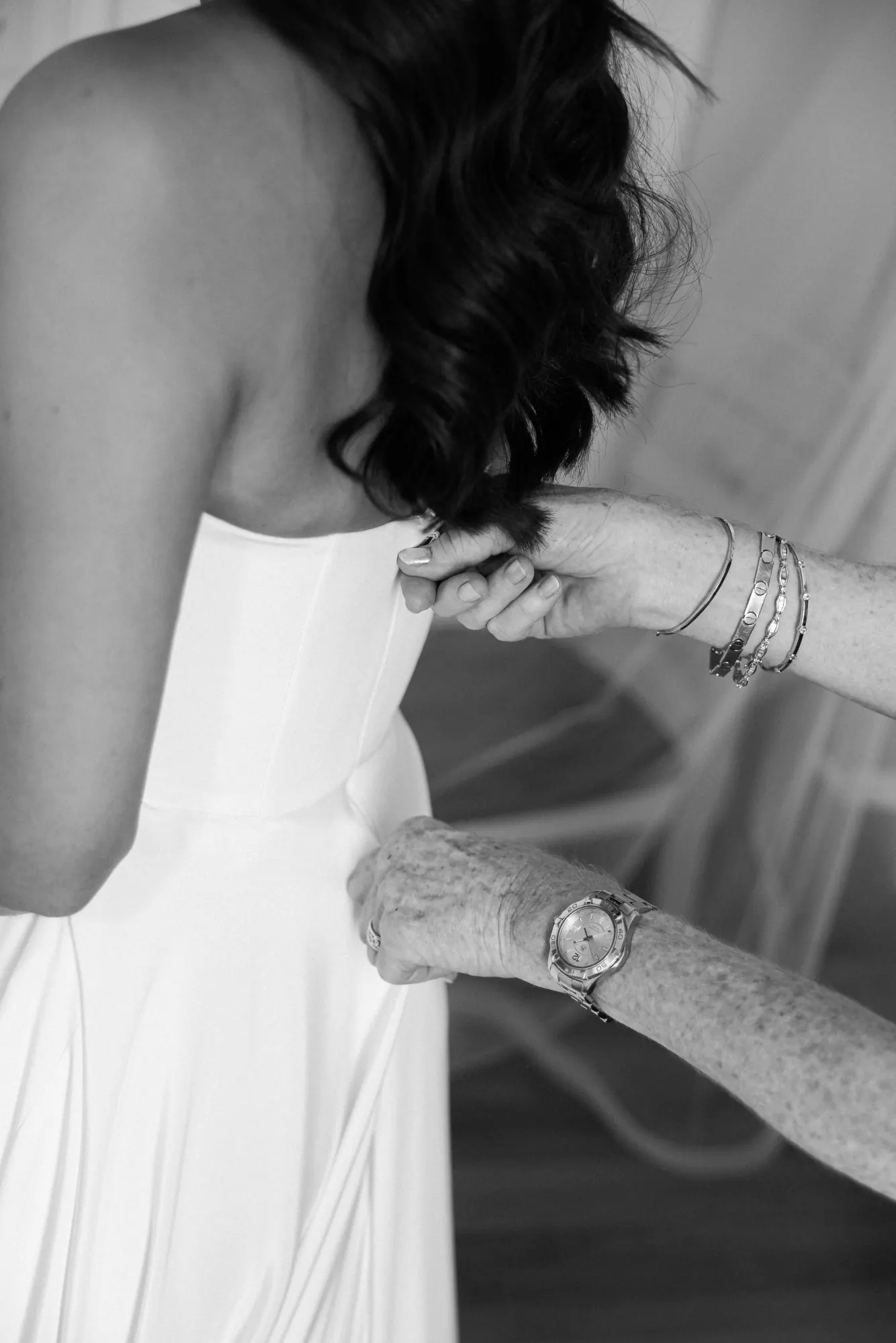 Black and white detail of the bride's gown being fastened