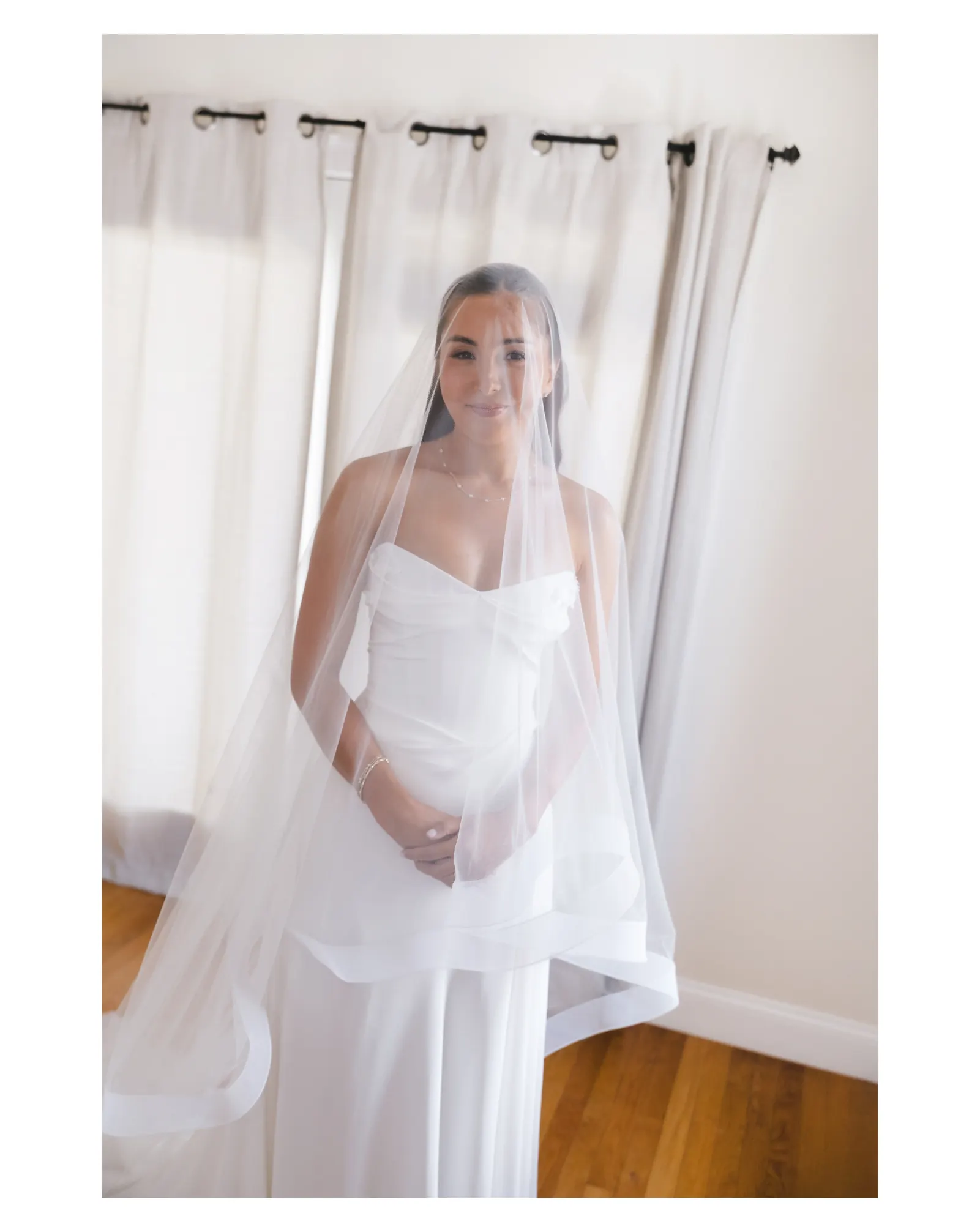 Bride with her veil over her face by the window light