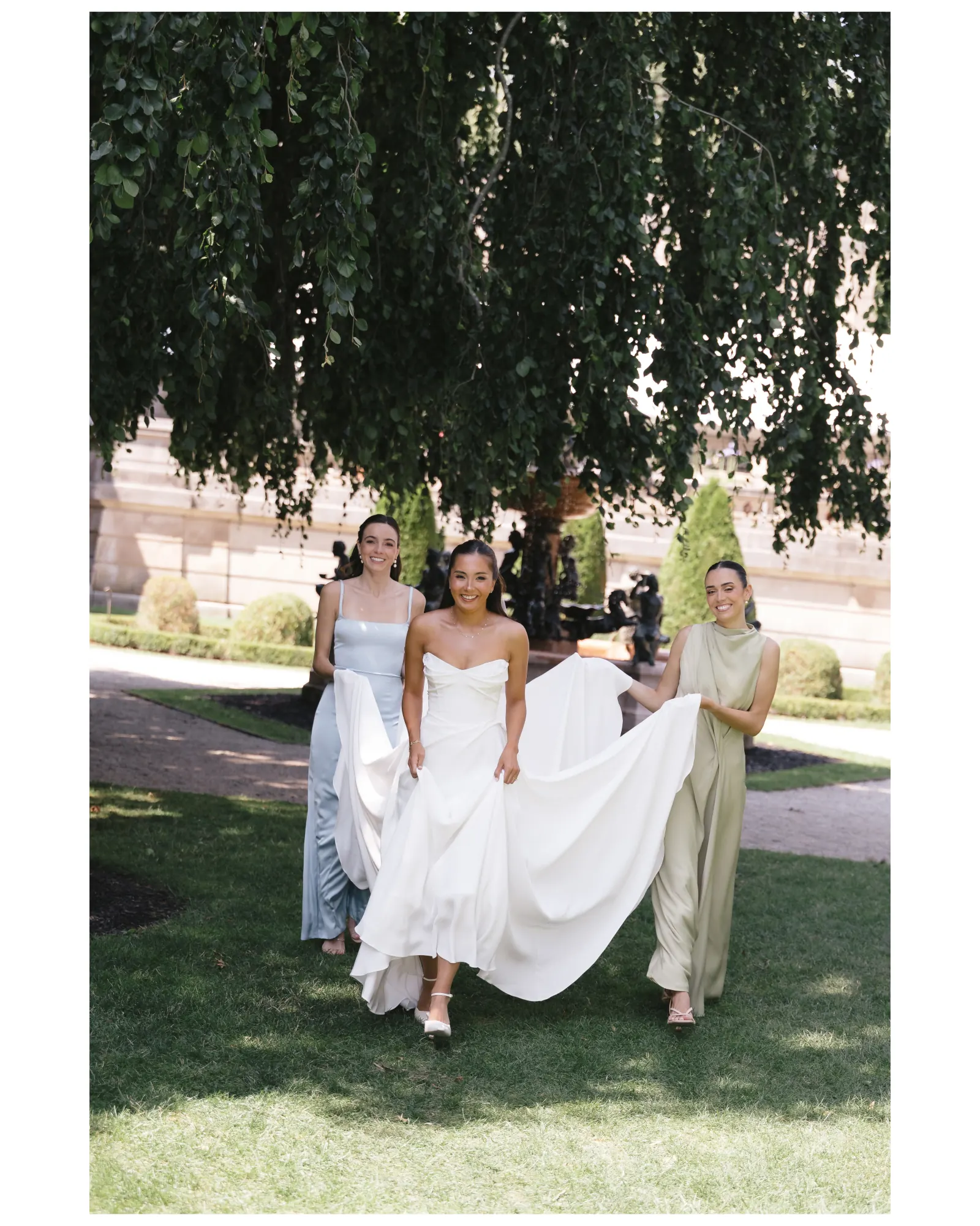 Bridesmaids carry the bride's train across the lawn at The Elms