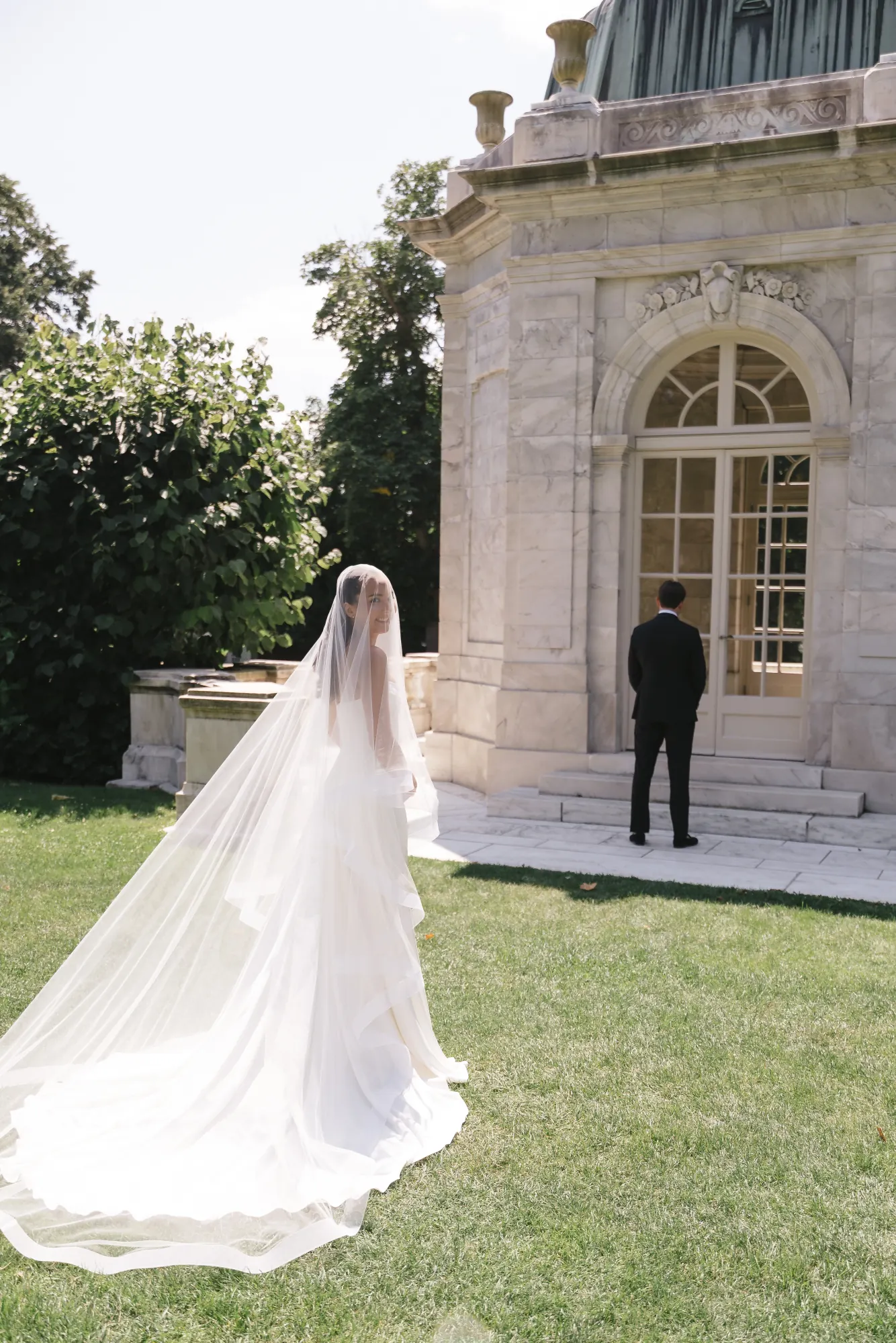Bride approaches the groom for their first look at The Elms teahouse, veil trailing
