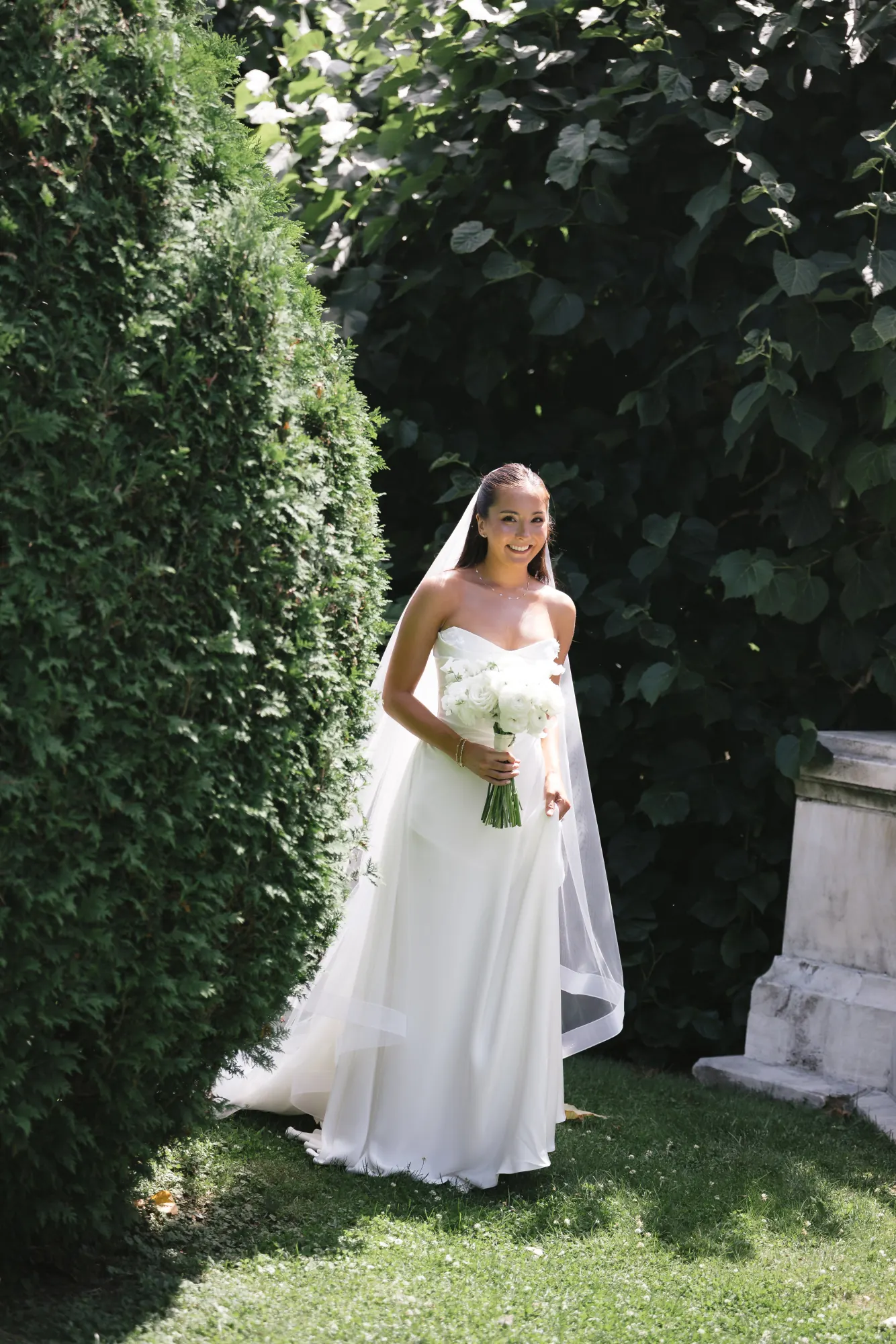 Bride walks the hedge path at The Elms with her bouquet