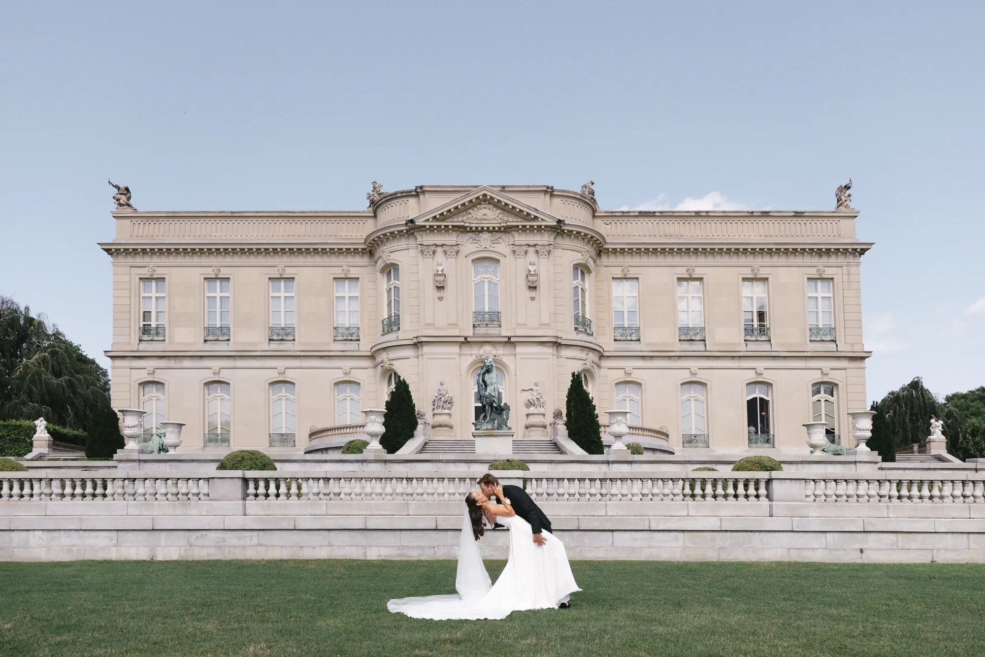 Bride and groom on the great lawn before the full facade of The Elms mansion