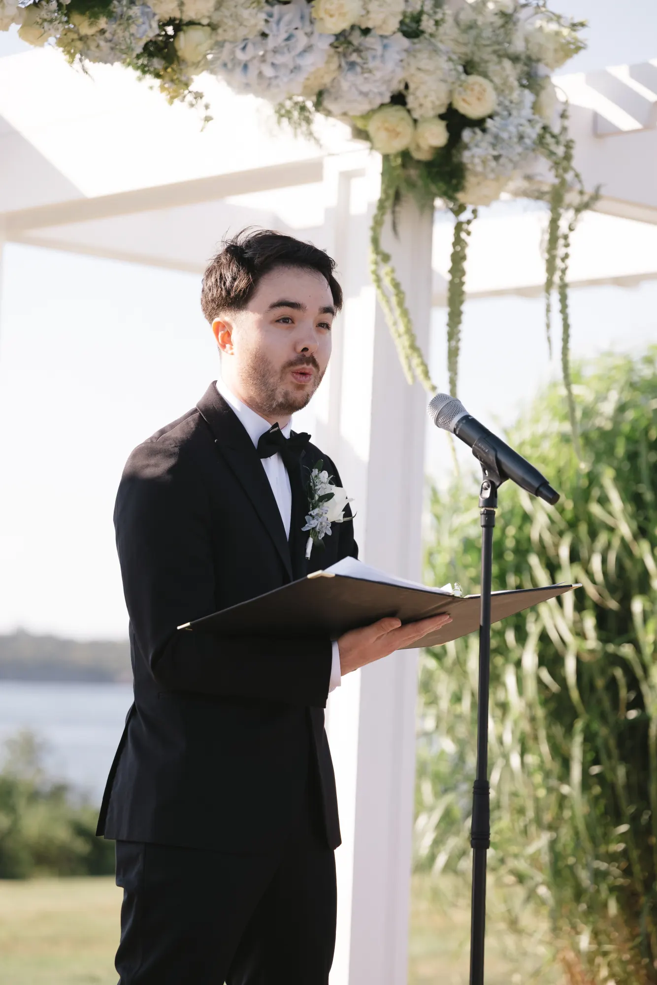 The bride's brother officiates at the microphone on the Bridge Lawn