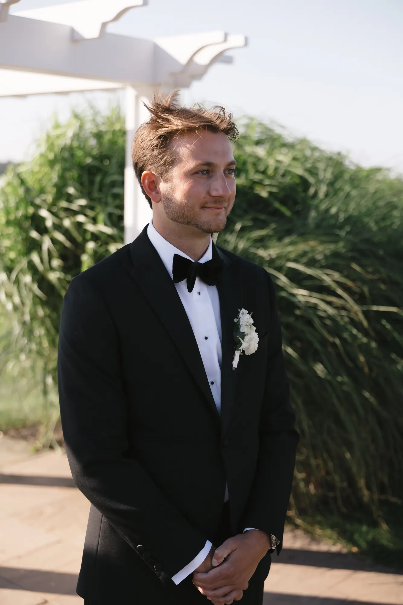 Groom waits at the pergola for the processional to begin