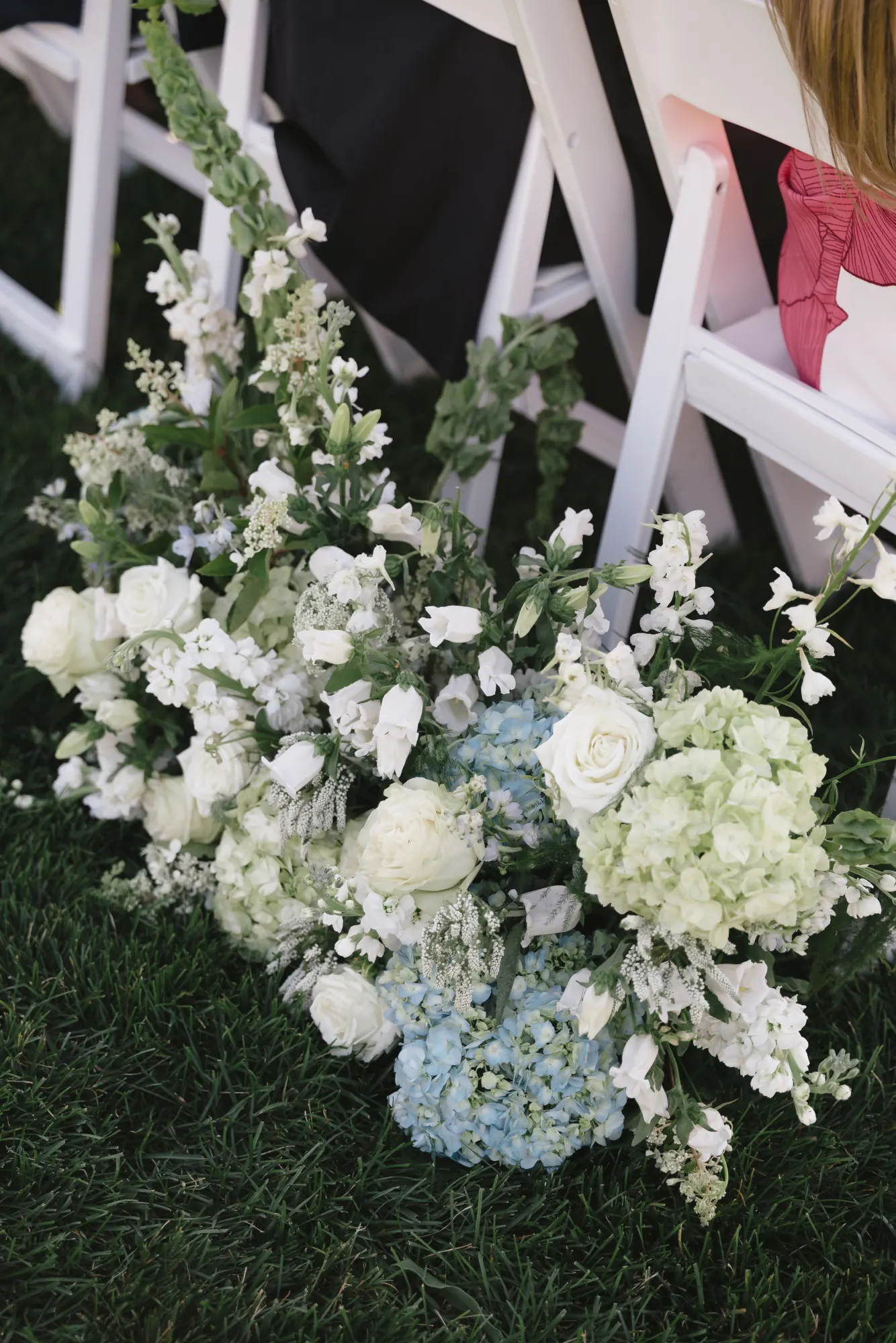 White and blue ceremony florals beside the pergola