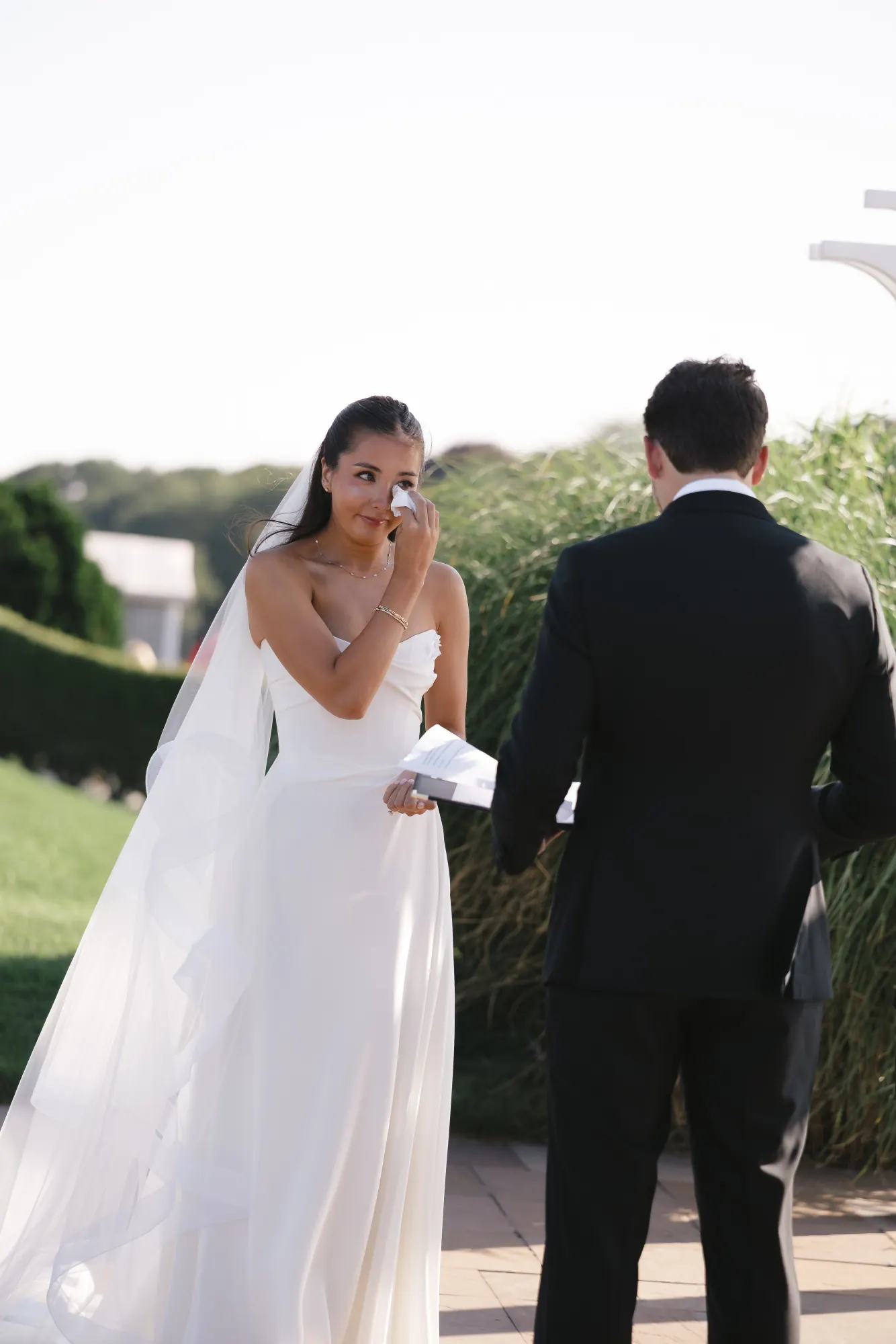The bride wipes a tear while reading her vows