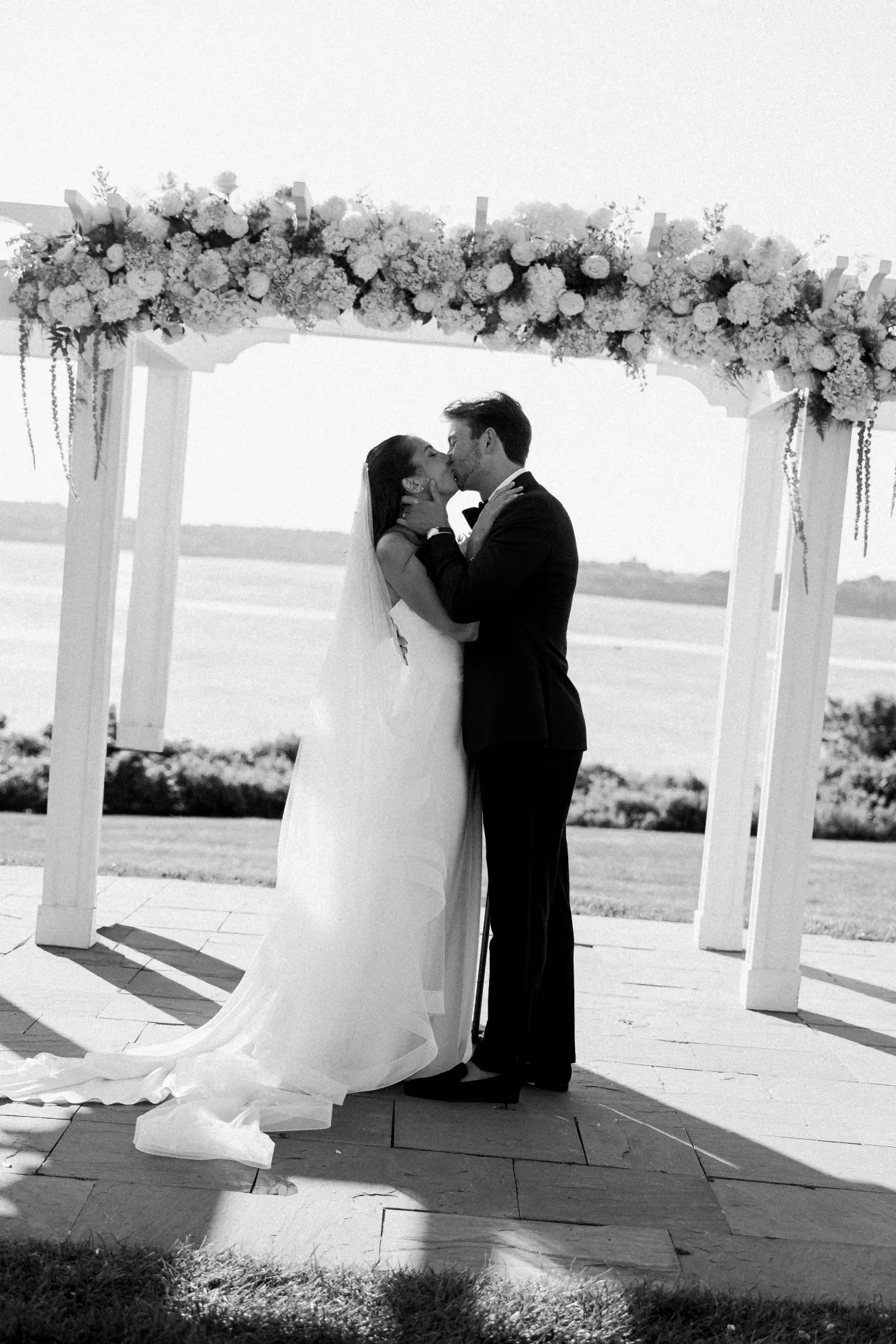 Black and white first kiss beneath the floral pergola
