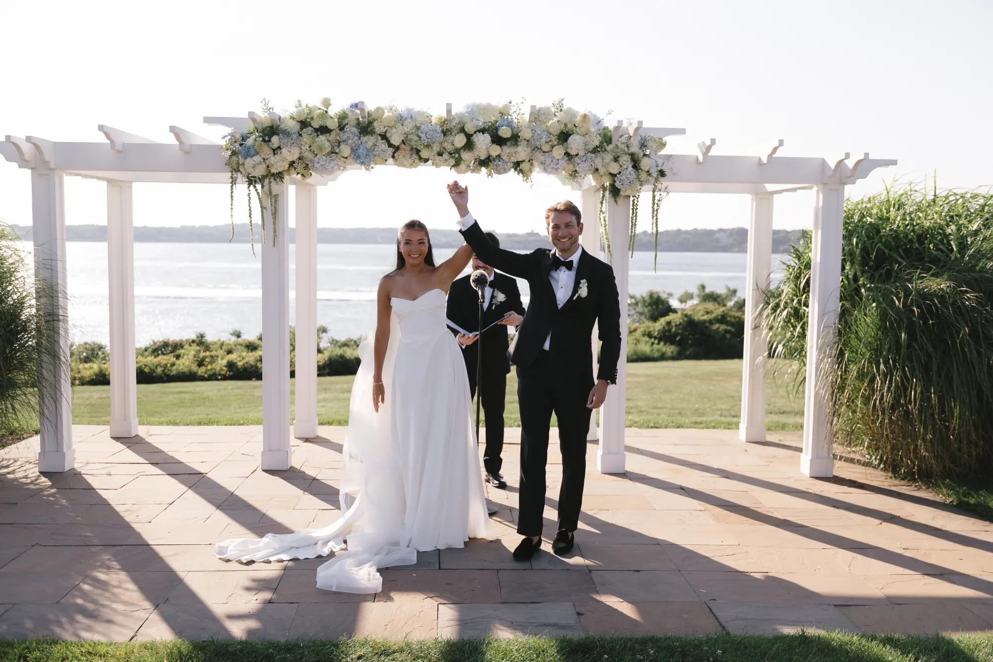 The newlyweds raise their arms in celebration at the pergola