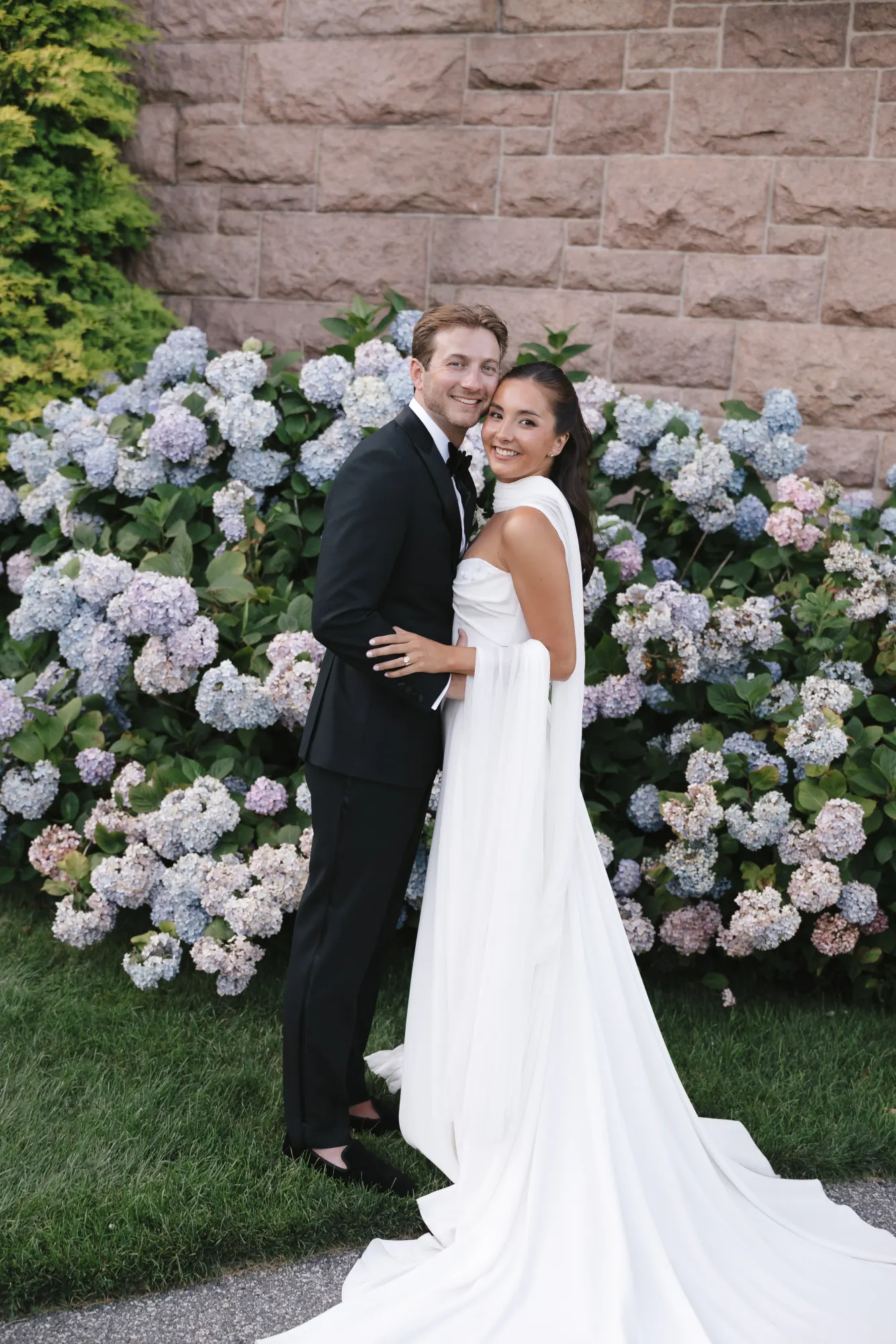 Couple portrait against the stone mansion and blue hydrangeas