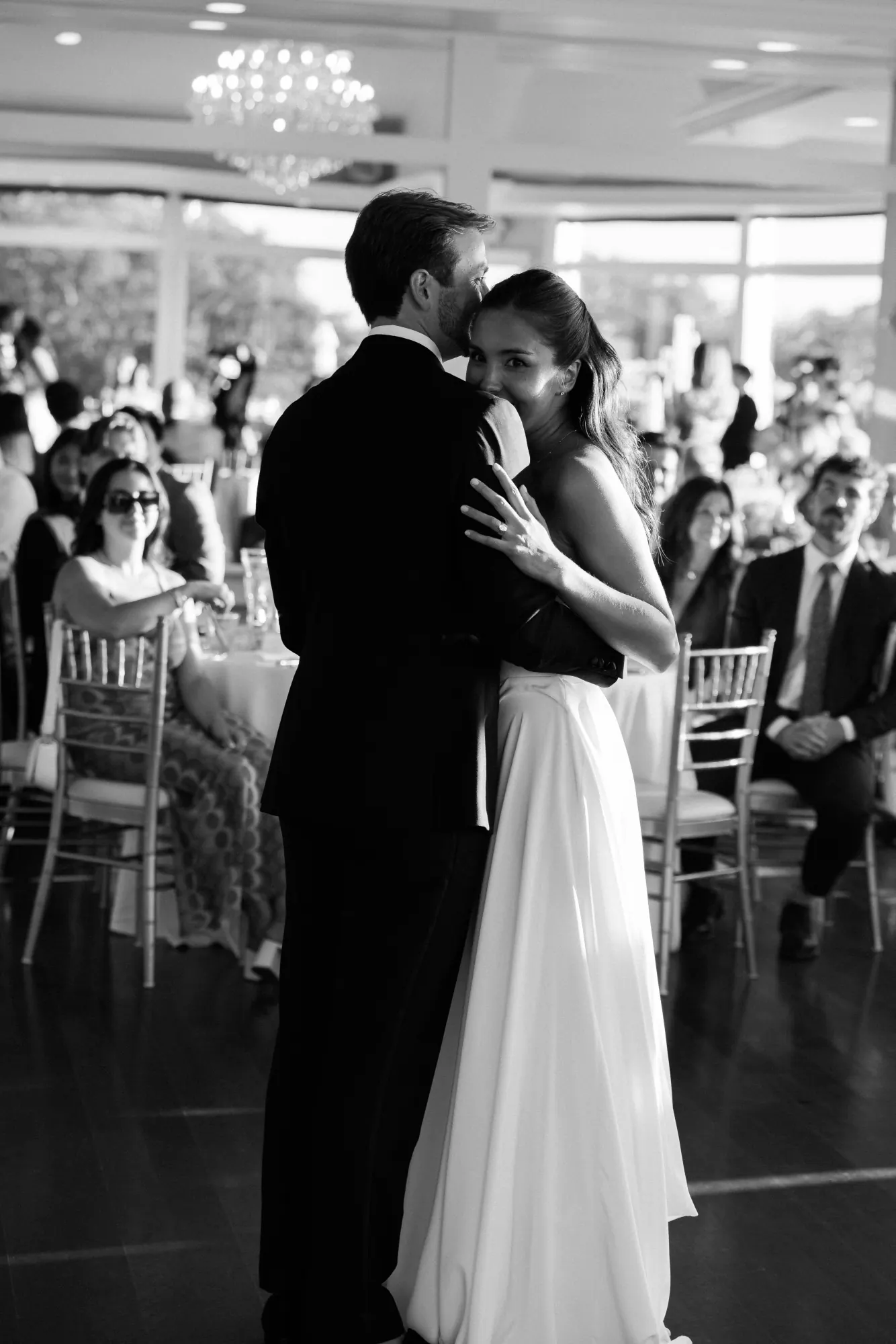 Black and white of the first dance with guests looking on