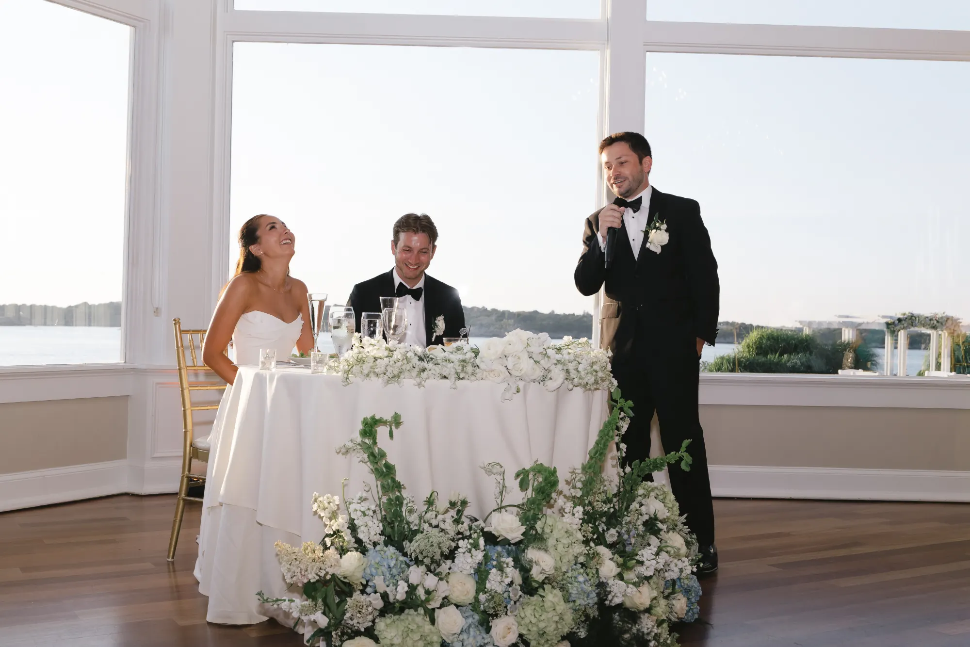 The couple laugh through the best man's toast
