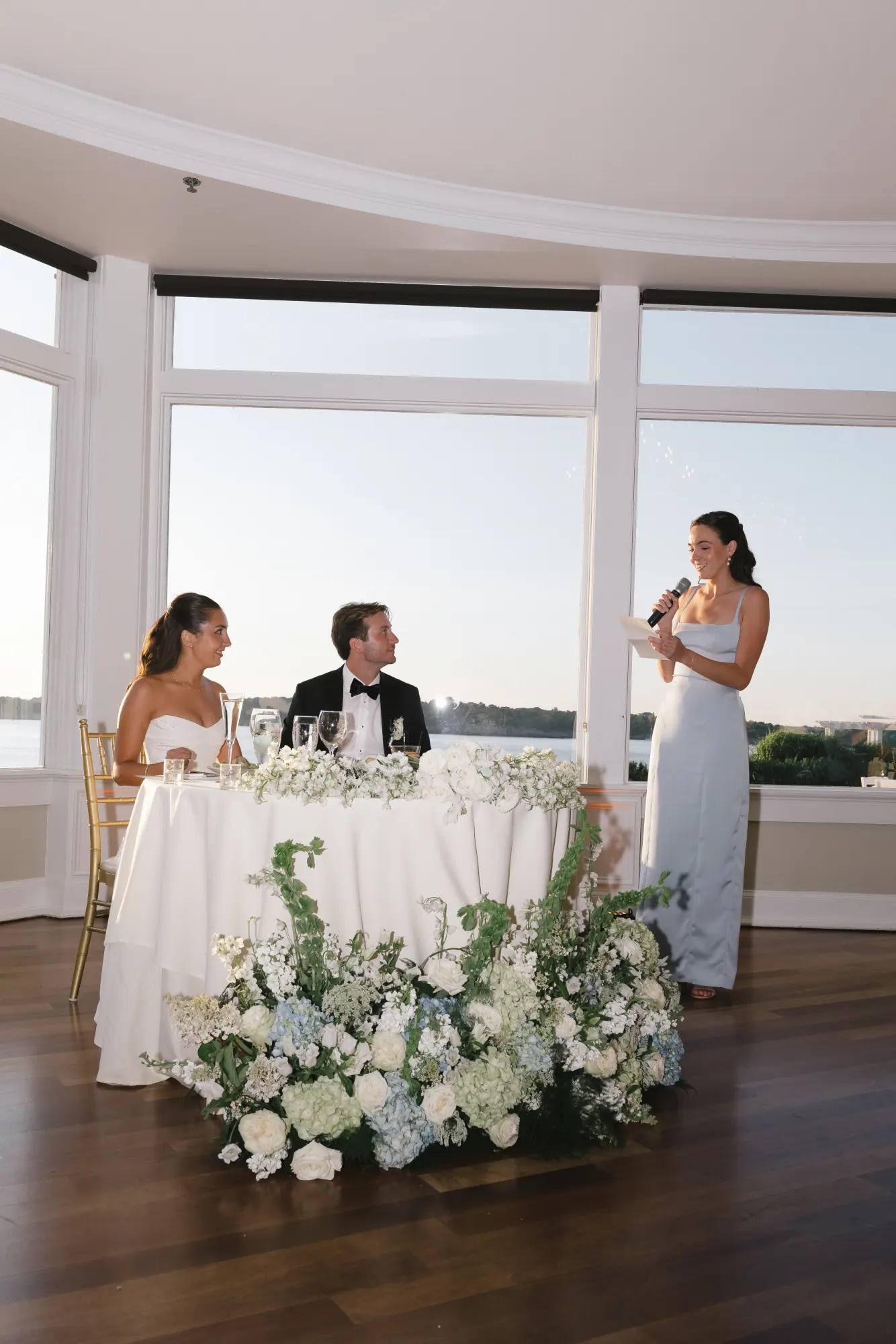 The maid of honor delivers her toast by the bay windows