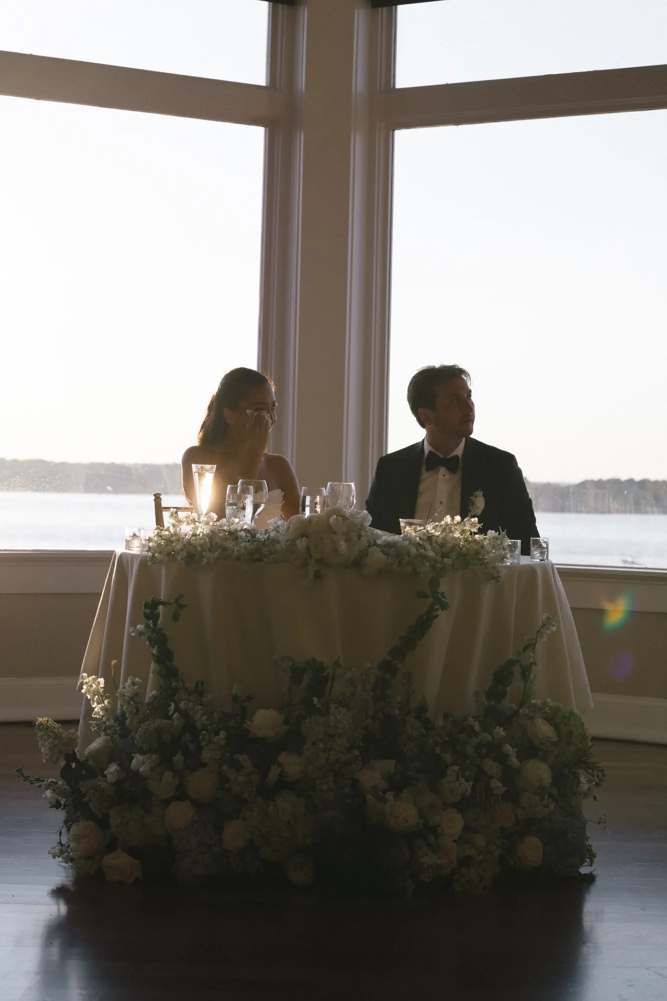 The sweetheart table backlit by the evening light over the bay