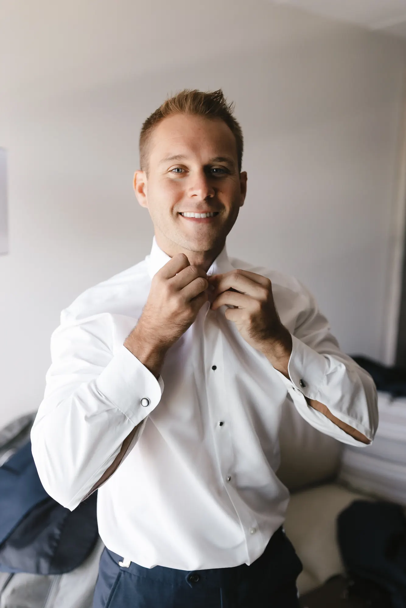 Groom fastens his black bow tie while getting ready for his Newport wedding