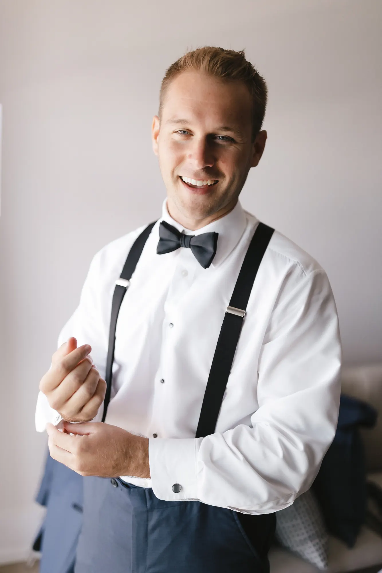 Groom in a black bow tie and suspenders getting ready at OceanCliff