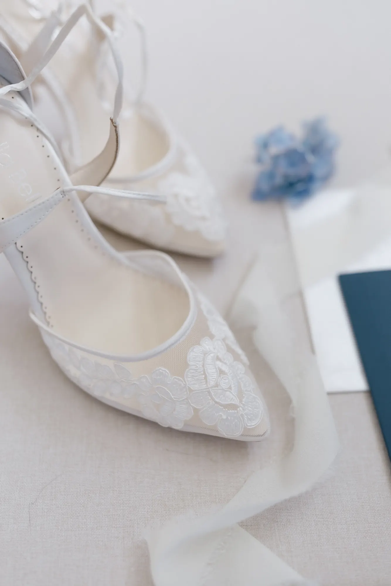Bride's white lace pointed-toe heels with blue hydrangea before her OceanCliff wedding