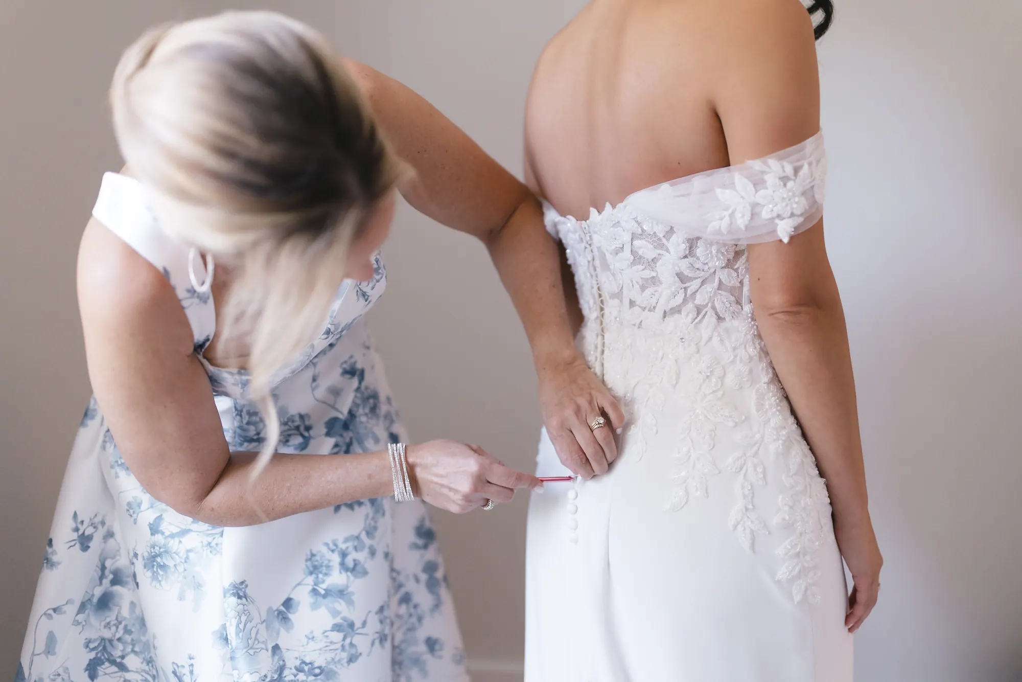 Fastening the back of the bride's lace wedding gown