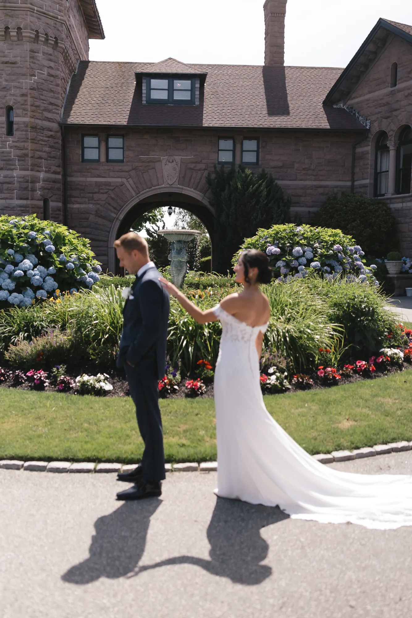 First look as the bride approaches the groom on the drive before the OceanCliff stone mansion
