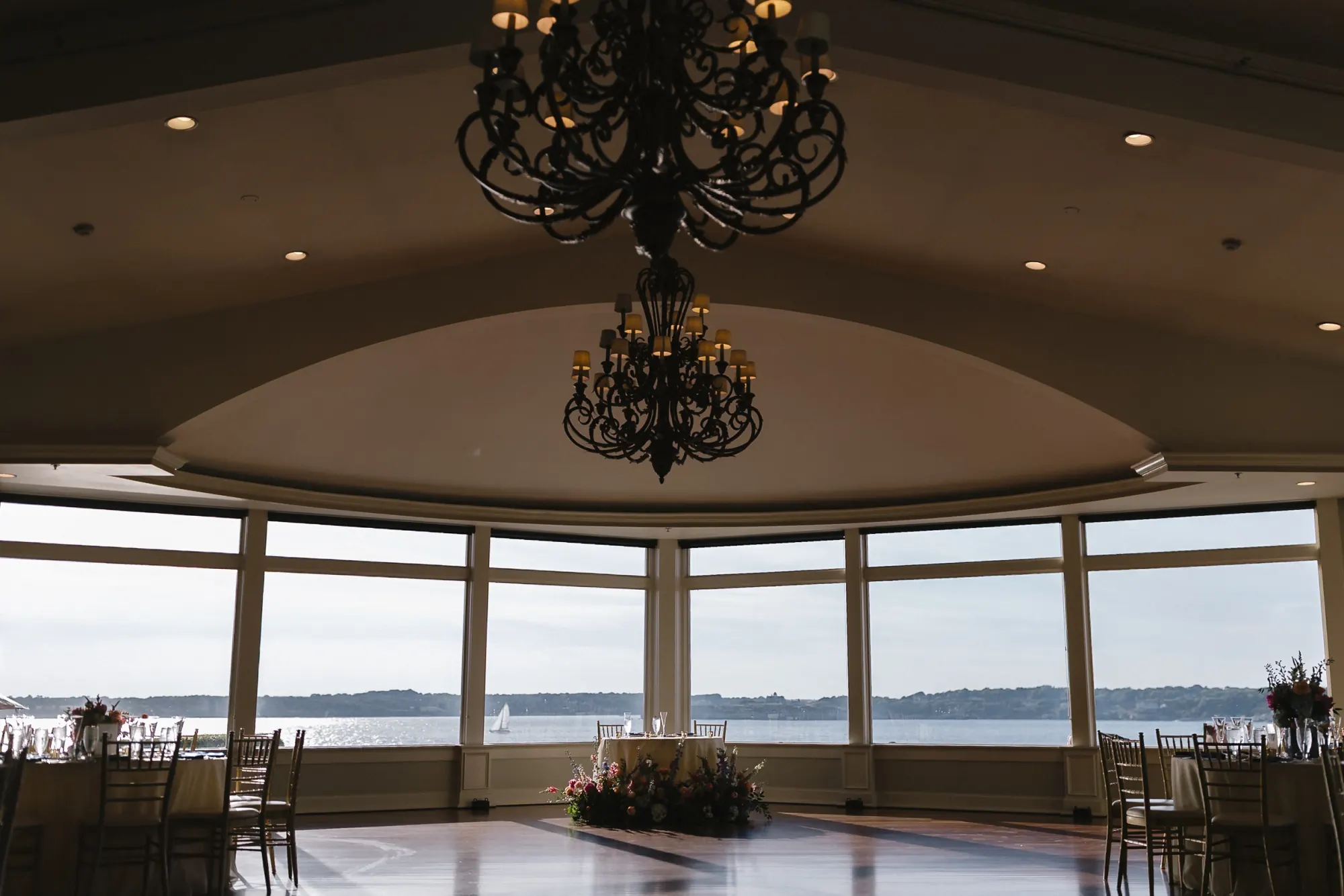 The OceanCliff ballroom with a chandelier and curved windows over Narragansett Bay