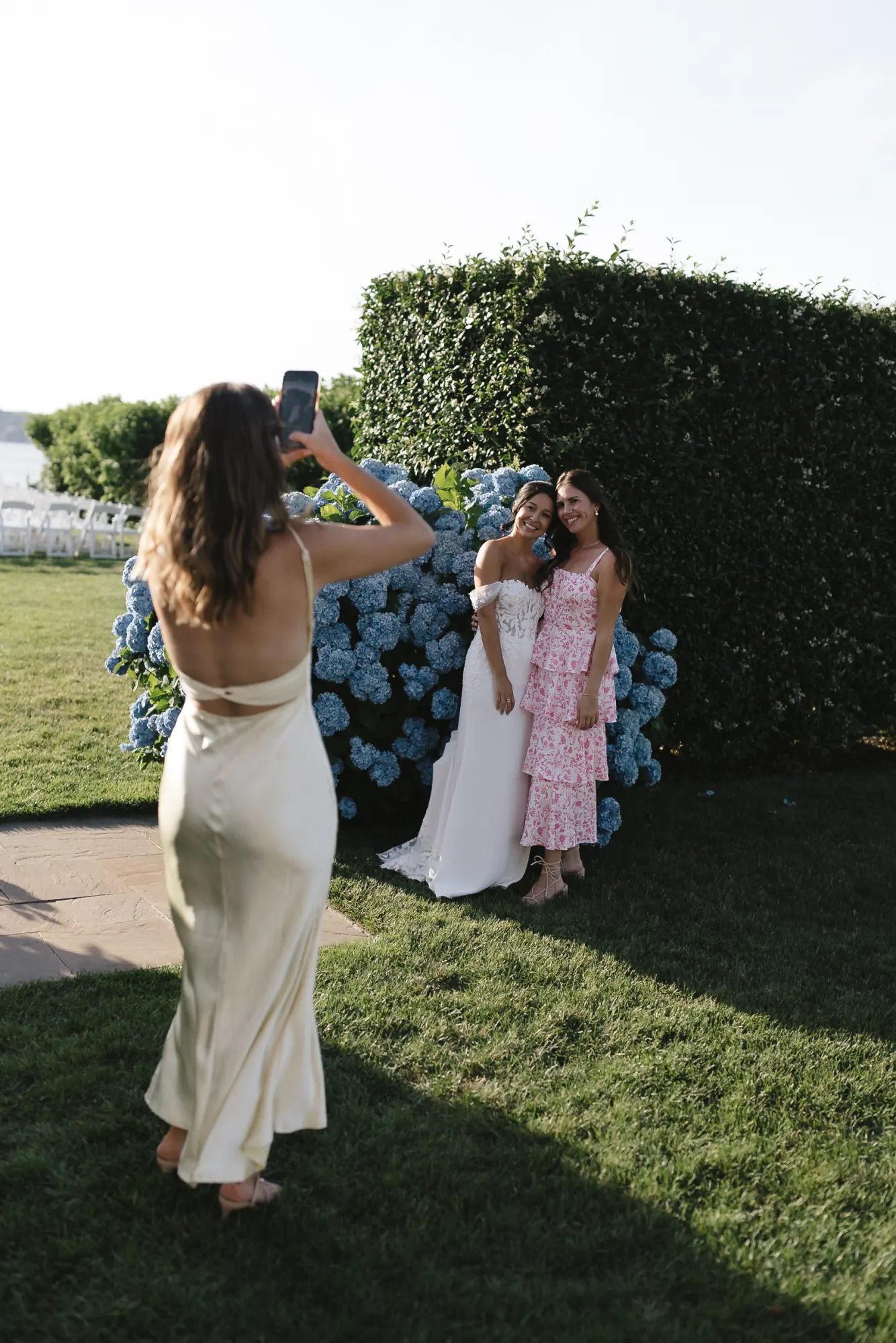 A bridesmaid photographs the bride on her phone during a candid Newport wedding moment