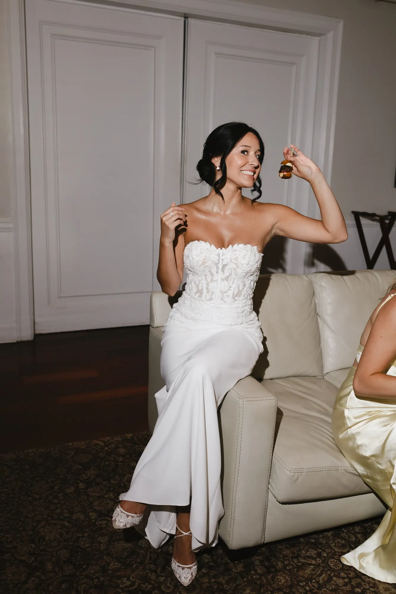Bride relaxes on a lounge with a drink, showing her lace heels at the OceanCliff reception