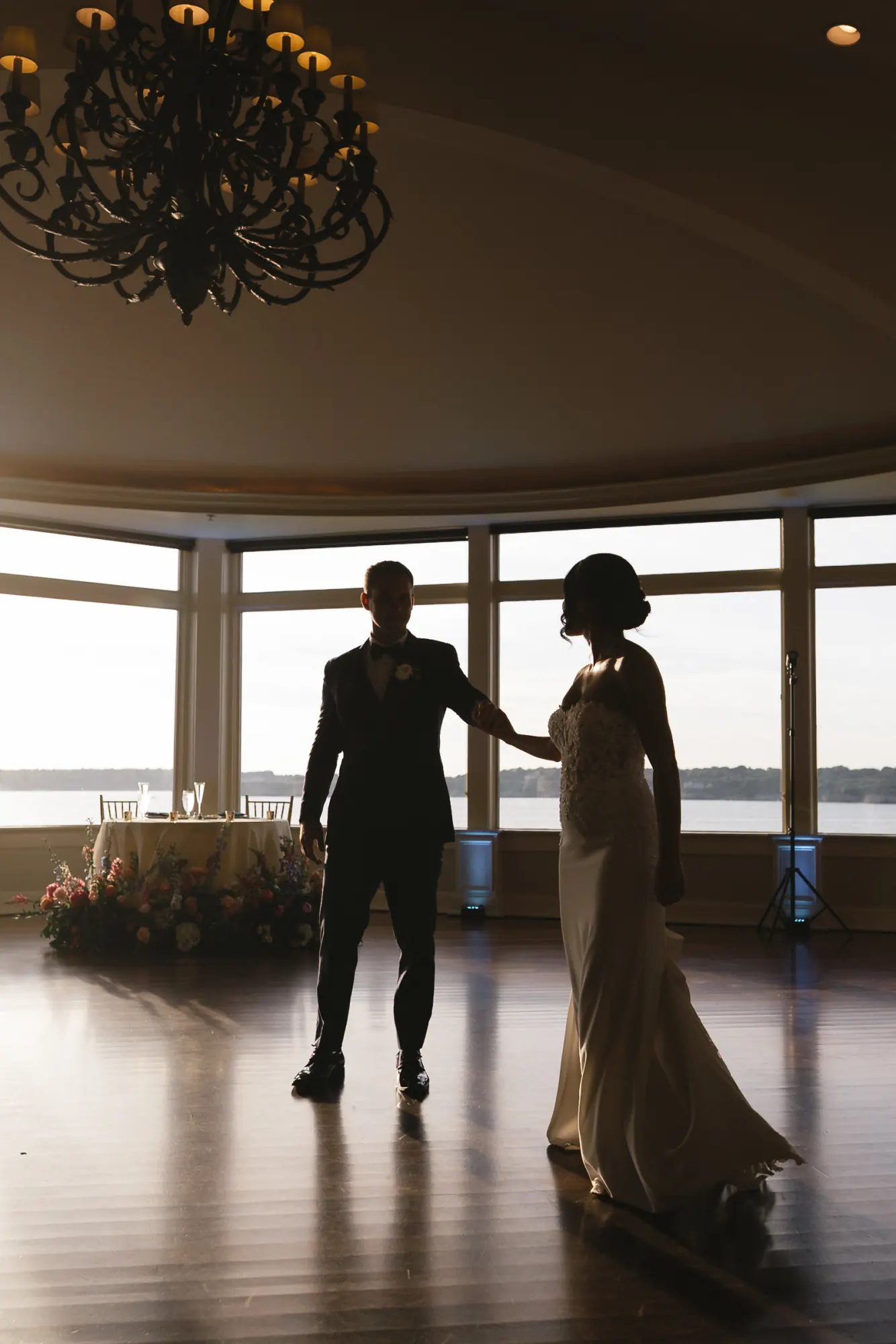 Bride and groom's first dance in silhouette against the bay windows at OceanCliff