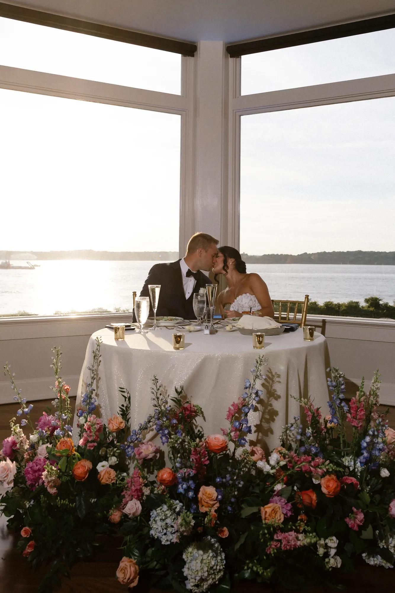 Sweetheart table with lush florals and a bay view at golden hour, OceanCliff reception