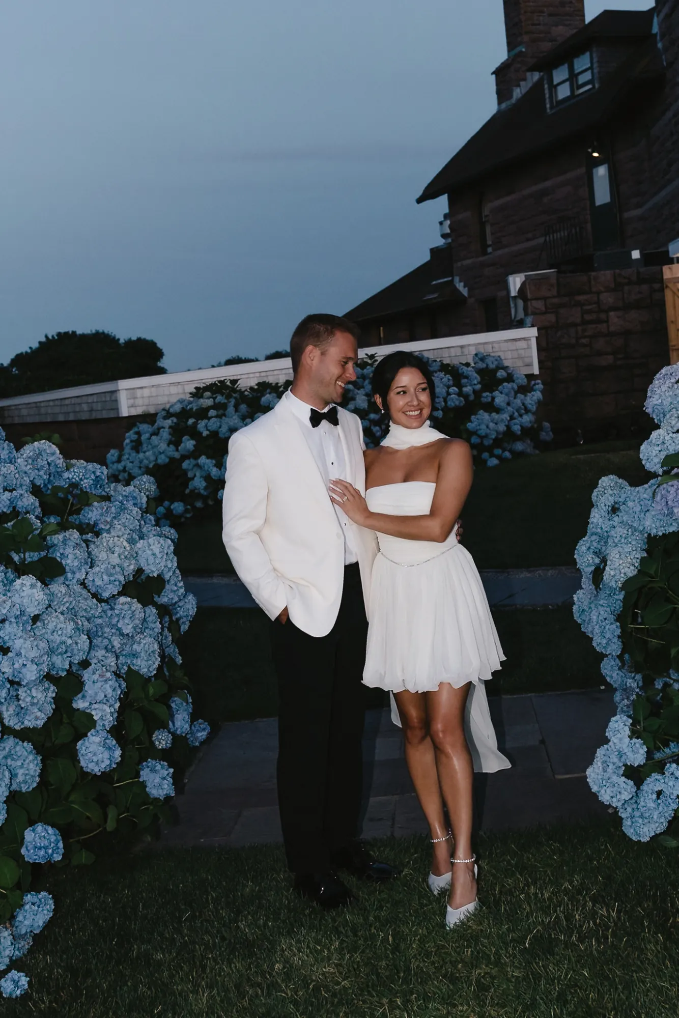 Jess and Brett among blue hydrangeas at dusk outside the OceanCliff mansion in Newport, Rhode Island